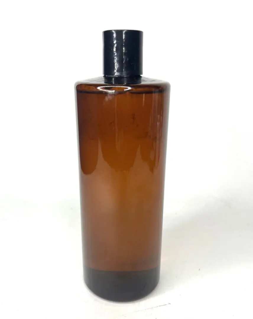 Tall amber glass bottle with black cap against white background. Tall amber glass bottle with black cap against white background.