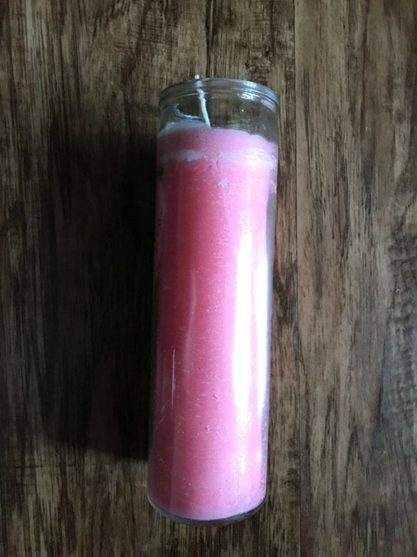 Pink glass jar candle on wood table.