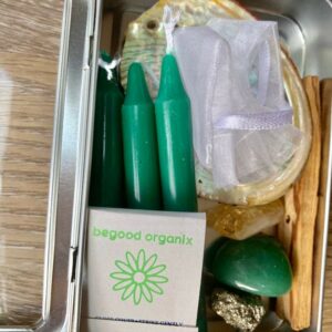 Green candles, crystals, and matches in a tin.