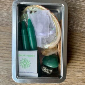 Tin box with green candles, crystals, and shell.