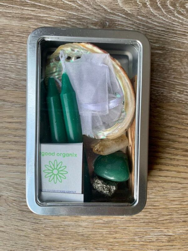 Tin box with green candles, crystals, and shell.