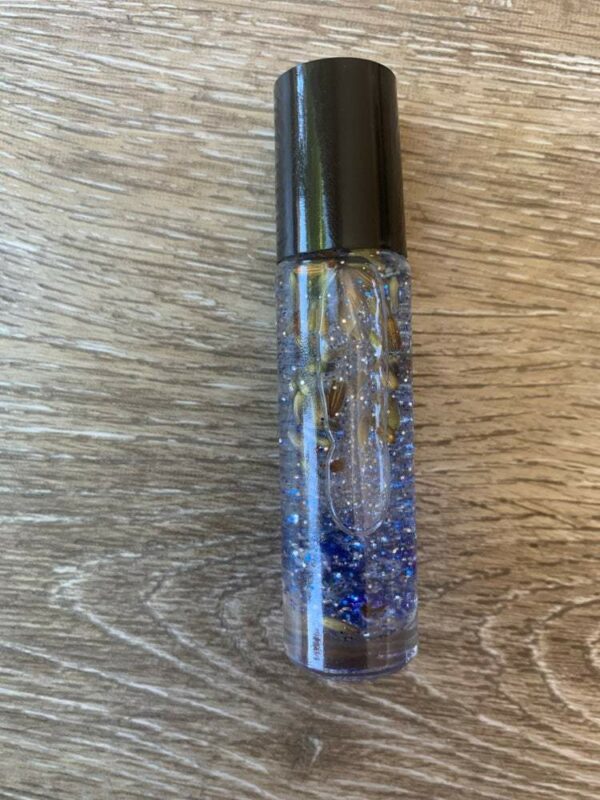 Glass roller bottle with blue glitter and herbs.