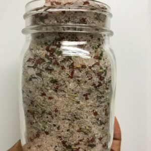 Jar of pink Himalayan salt with herbs.