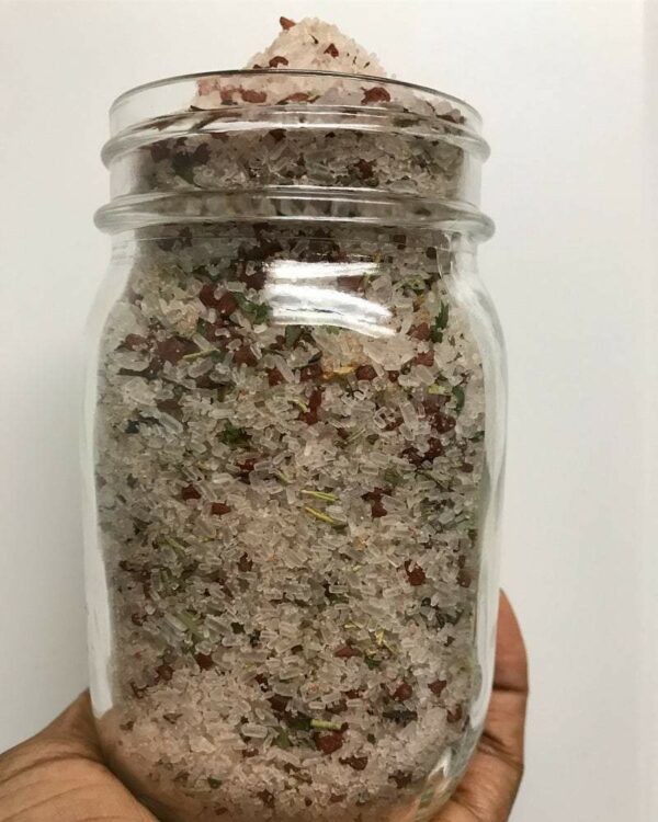 Jar of pink Himalayan salt with herbs.