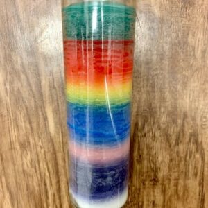 Rainbow layered glass candle on wood.