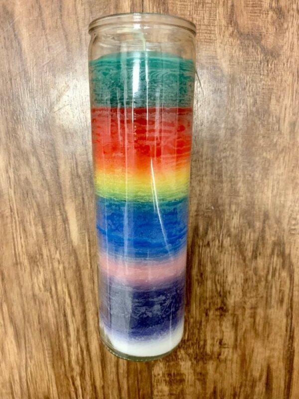 Rainbow layered glass candle on wood.