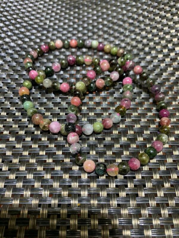 Multicolored gemstone beaded bracelet on black mat.