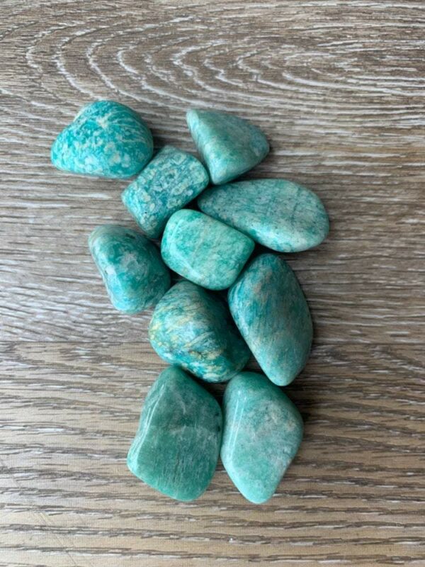 Green amazonite tumbled stones on wood.