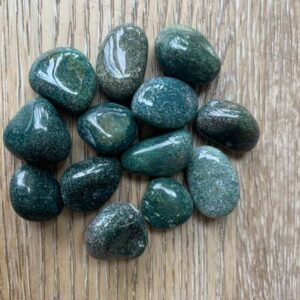 Green moss agate tumbled stones on wood.