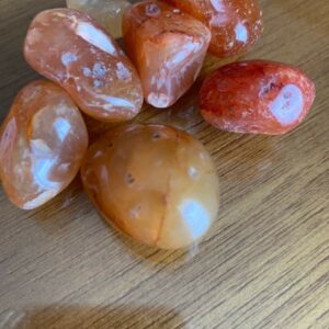 Six carnelian stones on wooden surface.