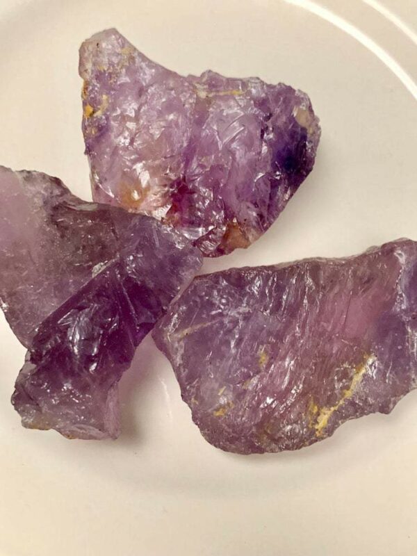 Three rough amethyst crystals on a plate.