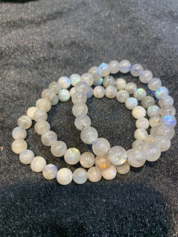 White moonstone beaded bracelets on black fabric.