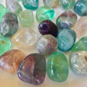 Rainbow fluorite tumbled stones on white background.