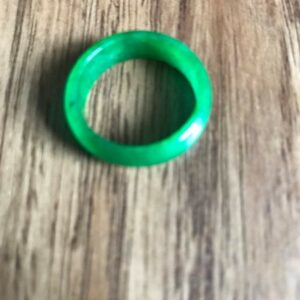 Green jade ring on wooden background.