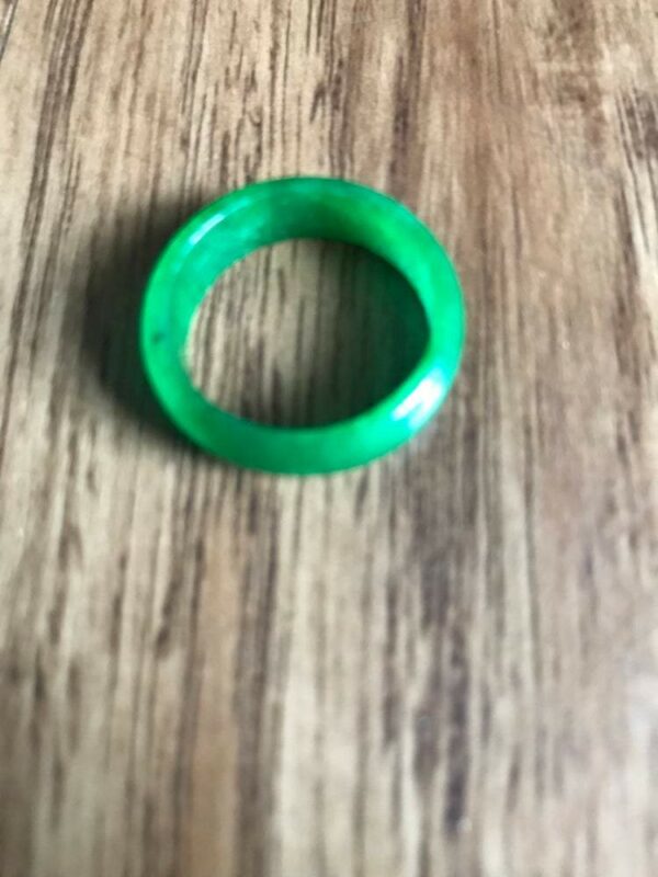 Green jade ring on wooden background.