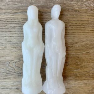 Two white candle figures of a man and woman.