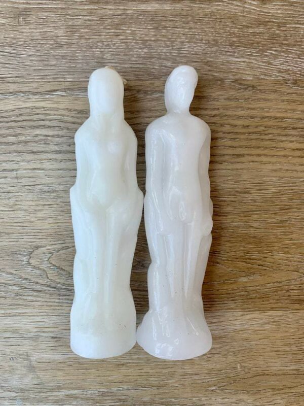 Two white candle figures of a man and woman.