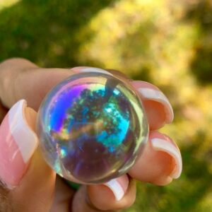 A hand holding a clear iridescent sphere.