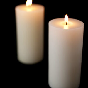 Two white candles lit against a black background.