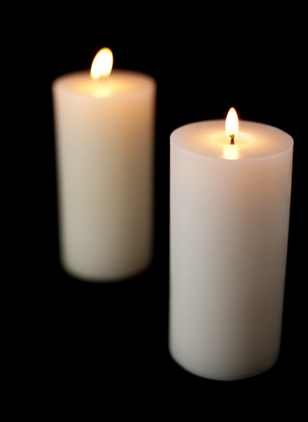 Two white candles lit against a black background.