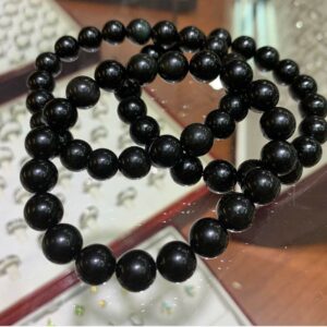 Two black beaded bracelets on a table.