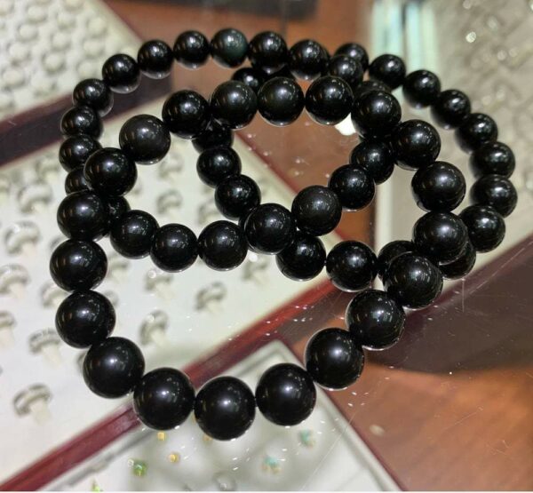 Two black beaded bracelets on a table.