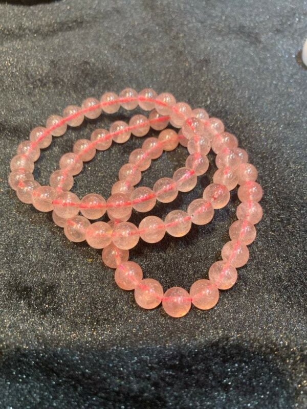 Pink quartz bead bracelet on black fabric.