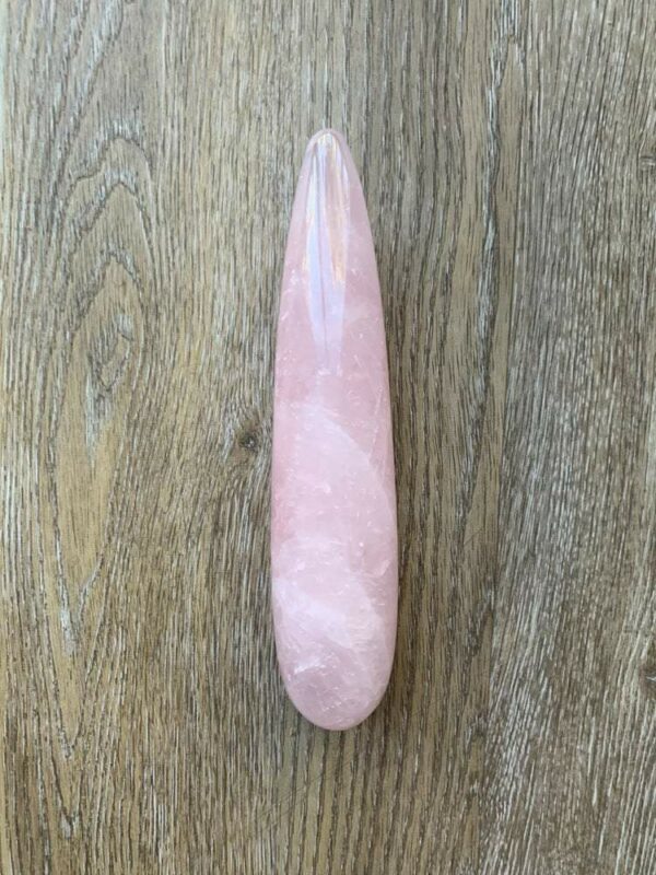 Pink rose quartz crystal on wood.