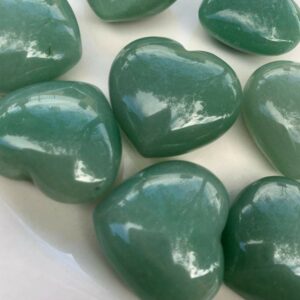 Green heart-shaped polished stones on white plate.