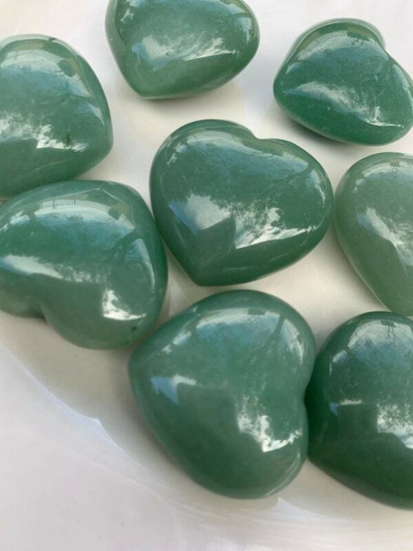 Green heart-shaped polished stones on white plate.