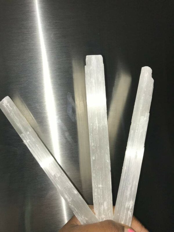 Three white selenite wands on a hand.