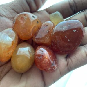 Hand holding orange and yellow carnelian stones.