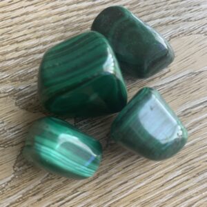 Four green malachite tumbled stones.