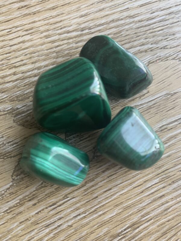 Four green malachite tumbled stones.