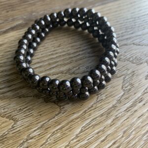 Black bead bracelet on wooden surface.