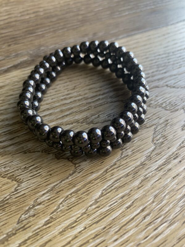 Black bead bracelet on wooden surface.