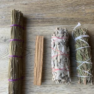 Four smudge sticks on a wooden surface.