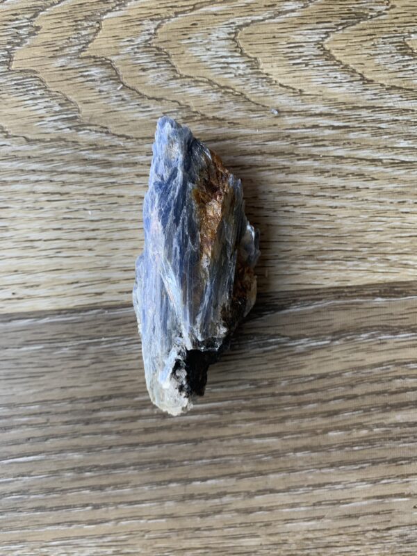 Blue kyanite crystal on woodgrain.