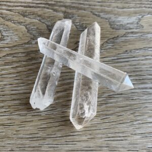 Three clear quartz crystals on wood.