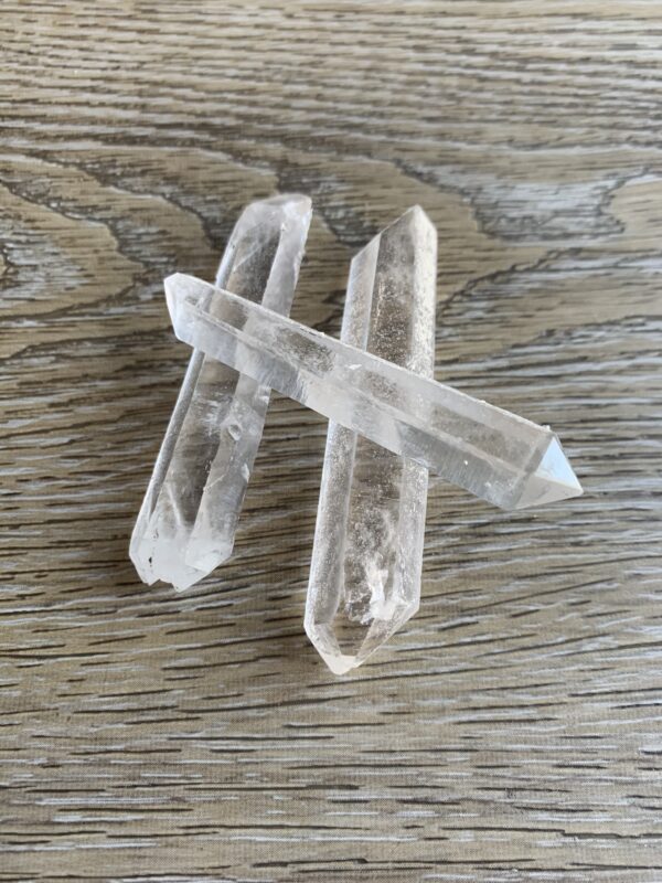 Three clear quartz crystals on wood.