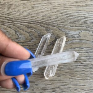 Three clear quartz crystals on wood.