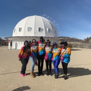 Group of people in tie-dye shirts in front of a white dome.