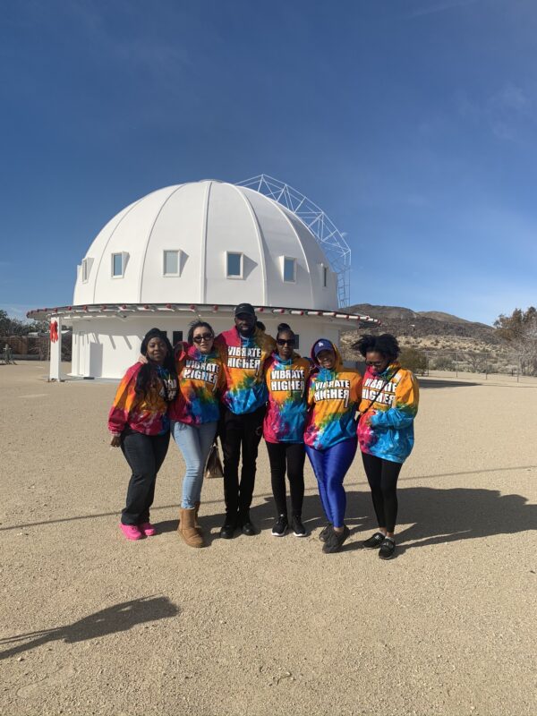 Group of people in tie-dye shirts in front of a white dome.