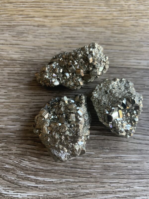 Three pyrite crystals on wood background.