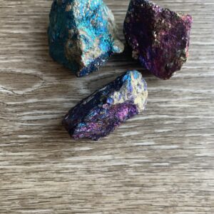 Three iridescent pyrite stones on wood.