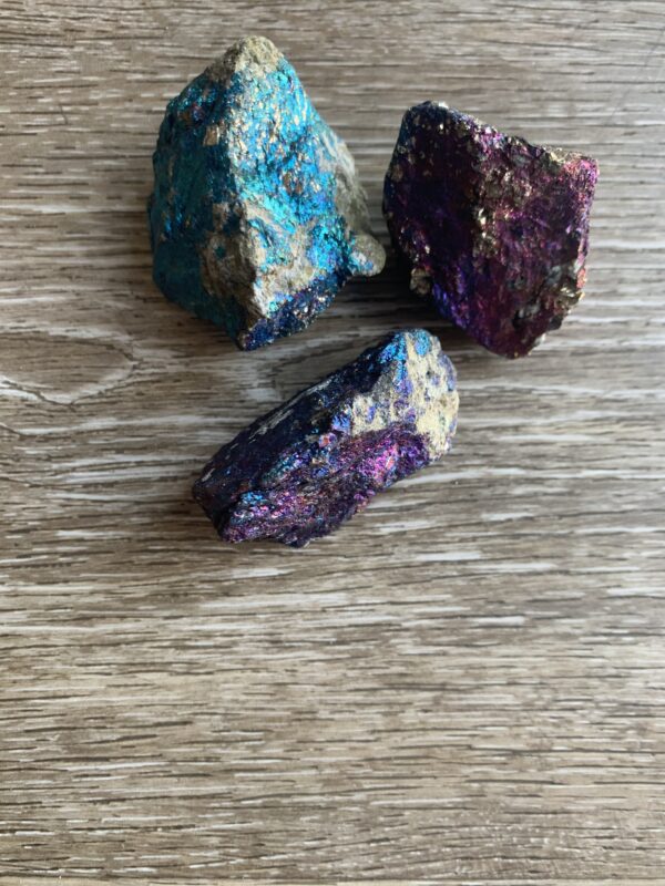 Three iridescent pyrite stones on wood.