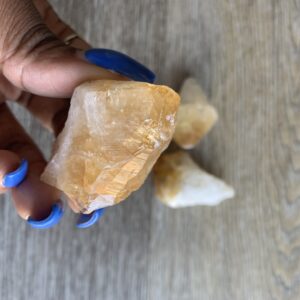 Hand holding a yellow citrine crystal.