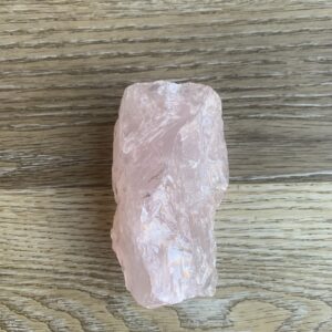 Pink quartz crystal on wood background.