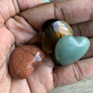 Three heart-shaped crystals in a hand.