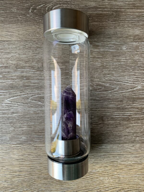 Amethyst crystal water bottle on wood.